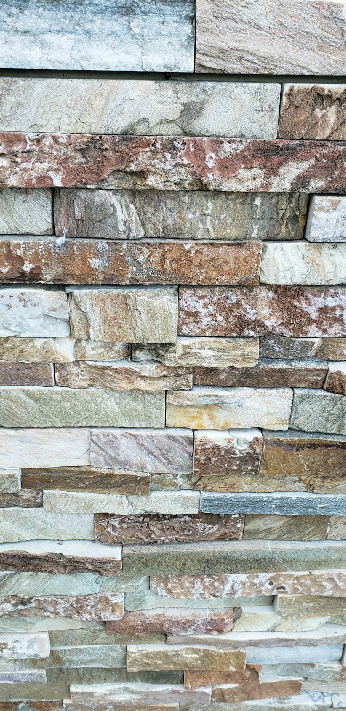 A wall built with stacked rectangular natural stones.